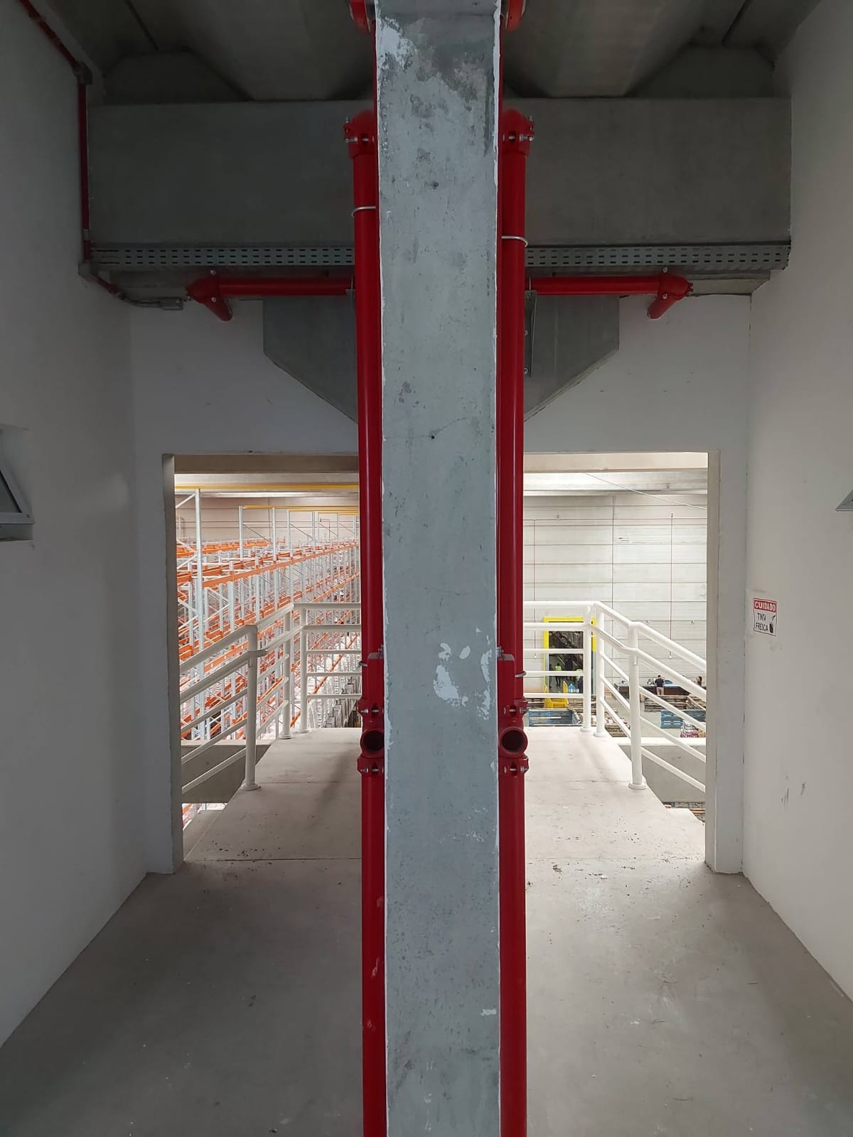 Instalação de tubulação vermelha de hidrante em pilar de concreto em galpão industrial