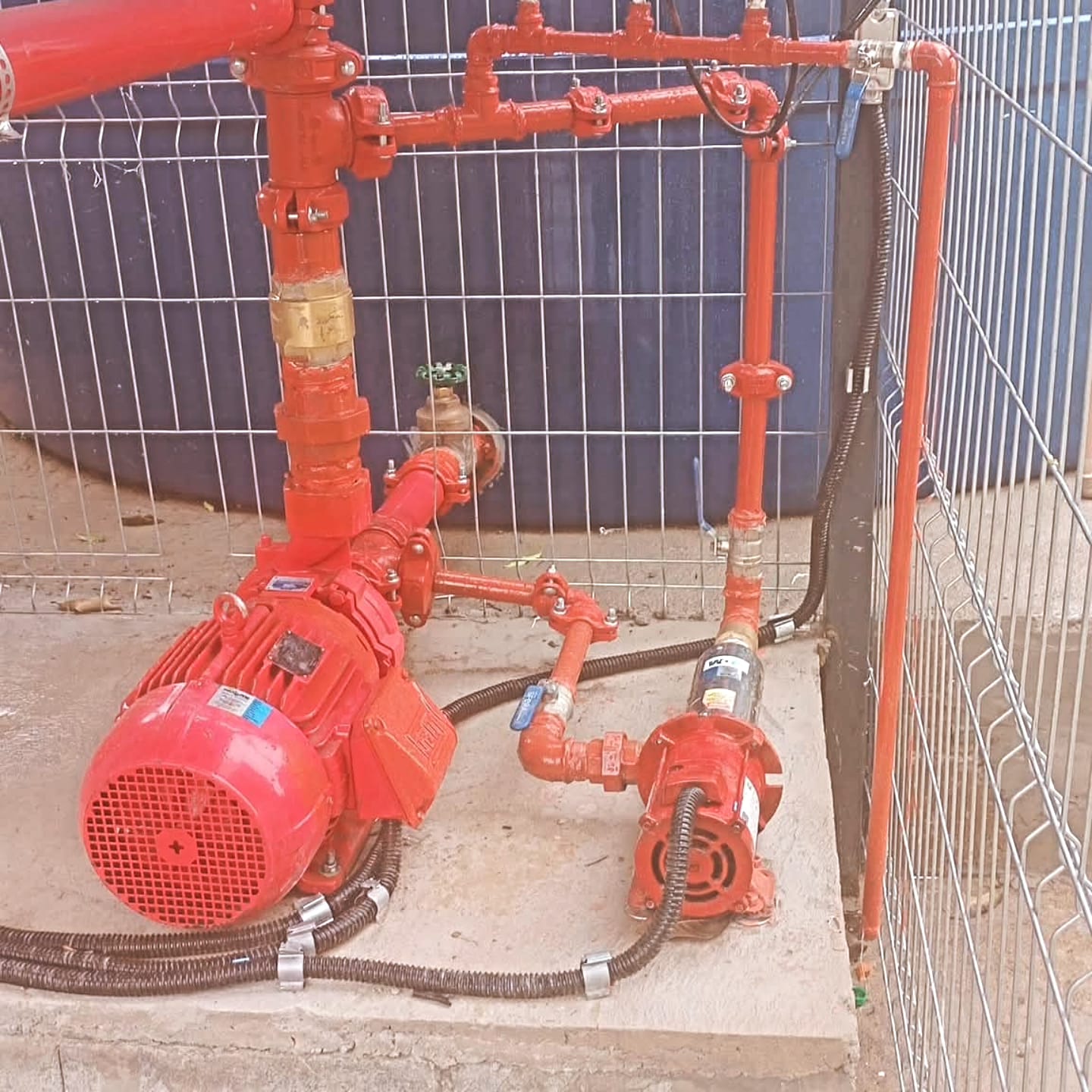Conjunto de bombas e tubulações vermelhas montadas em obra